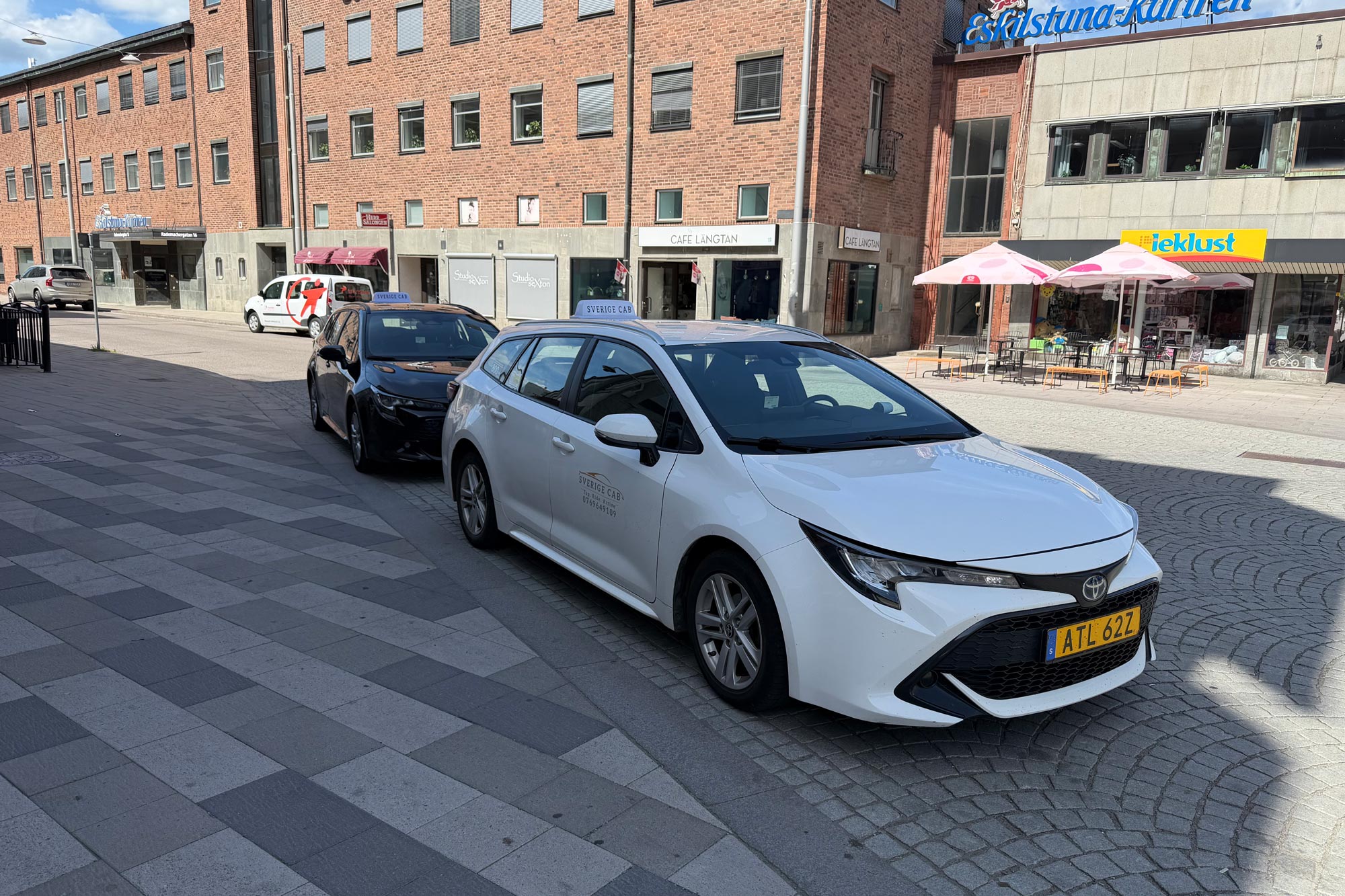 Kvinna lutar sig mot framdörren på en gul taxi på stadsgata