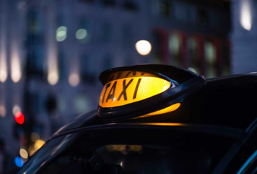 Närbild av gul upplyst taxiskylt på ett tak